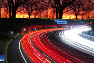 time elapsed image of headlights and taillights on trafficulated interstate below a distant fire forest fire