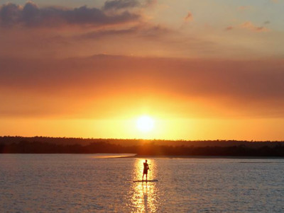 silhoutte of man against sunset paddle boarding