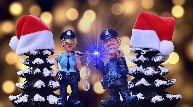 caricature of police with handcuffs and nightsticks posing between Christmas trees adorned with Santa hats