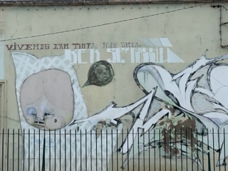 mural of face emerging from hood with Portuguese caption reading: We live with ink on our fingertips