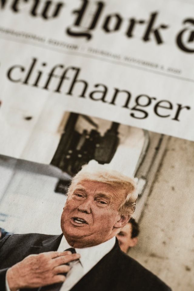 pic of newspaper headline reading 'Cliffhanger' with grainy photo of Trump grasping his tie knot like a sweating Rodney Dangerfield